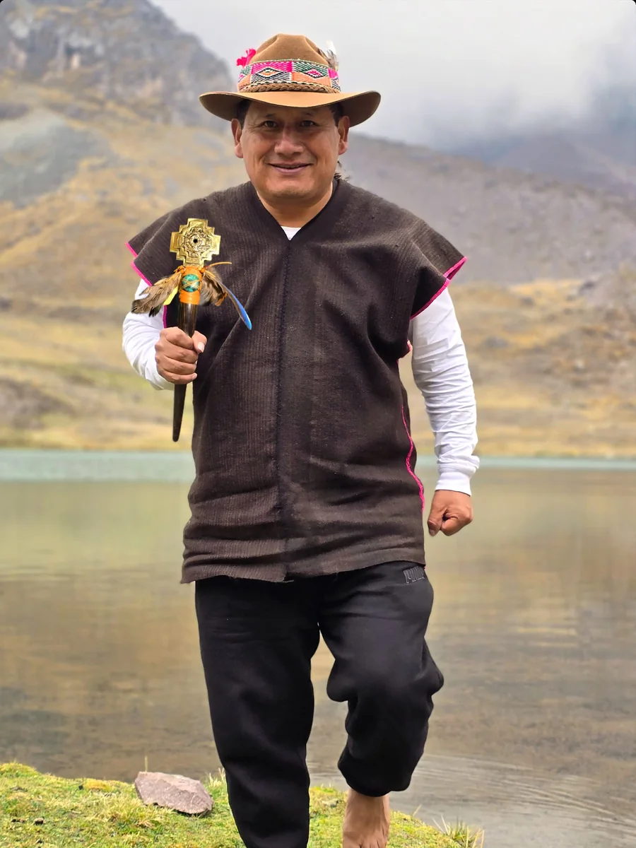 WillkaRuna Victor holding his staff beside a high Andean lagoon